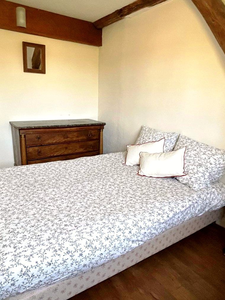 Une chambre, couvre-lit fleuri et commode à dessus de marbre