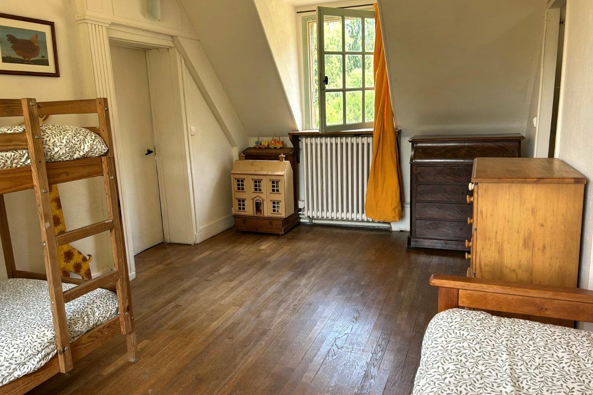 Une chambre d’enfants, lits superposés, maison de poupée en bois et fenêtre sur le jardin