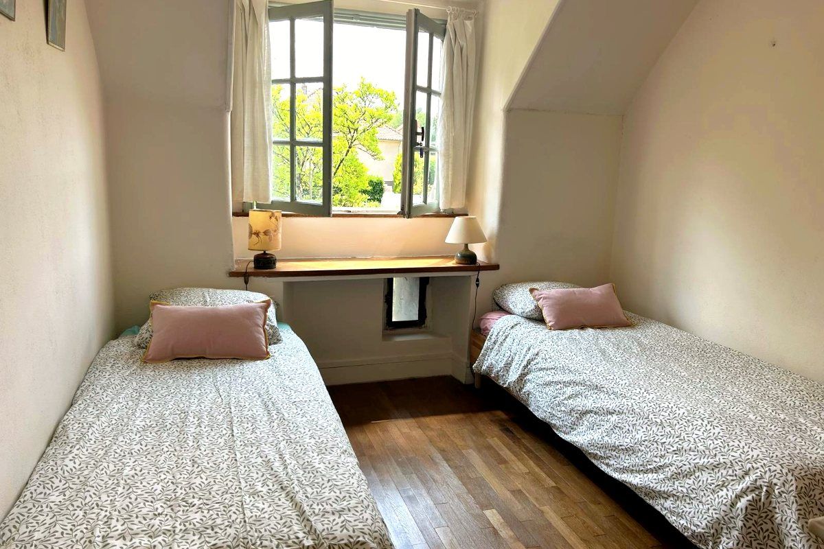 Une chambre à deux lits simples de part et d’autre d’une fenêtre profonde