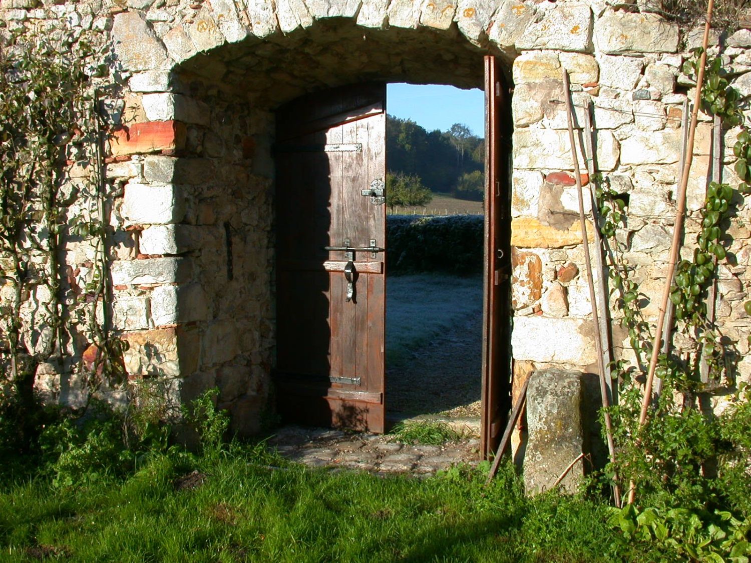 La porte du mur ouverte sur le pré givré, au petit matin
